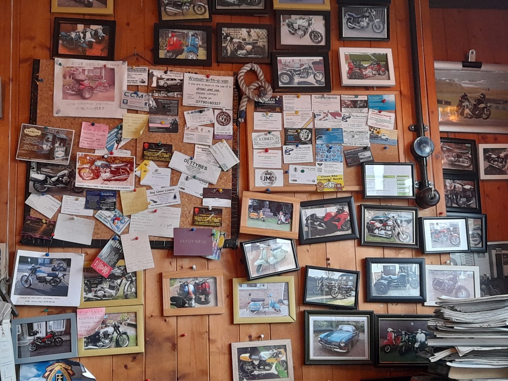 The workshop wall covered in framed photographs of vehicles and notes