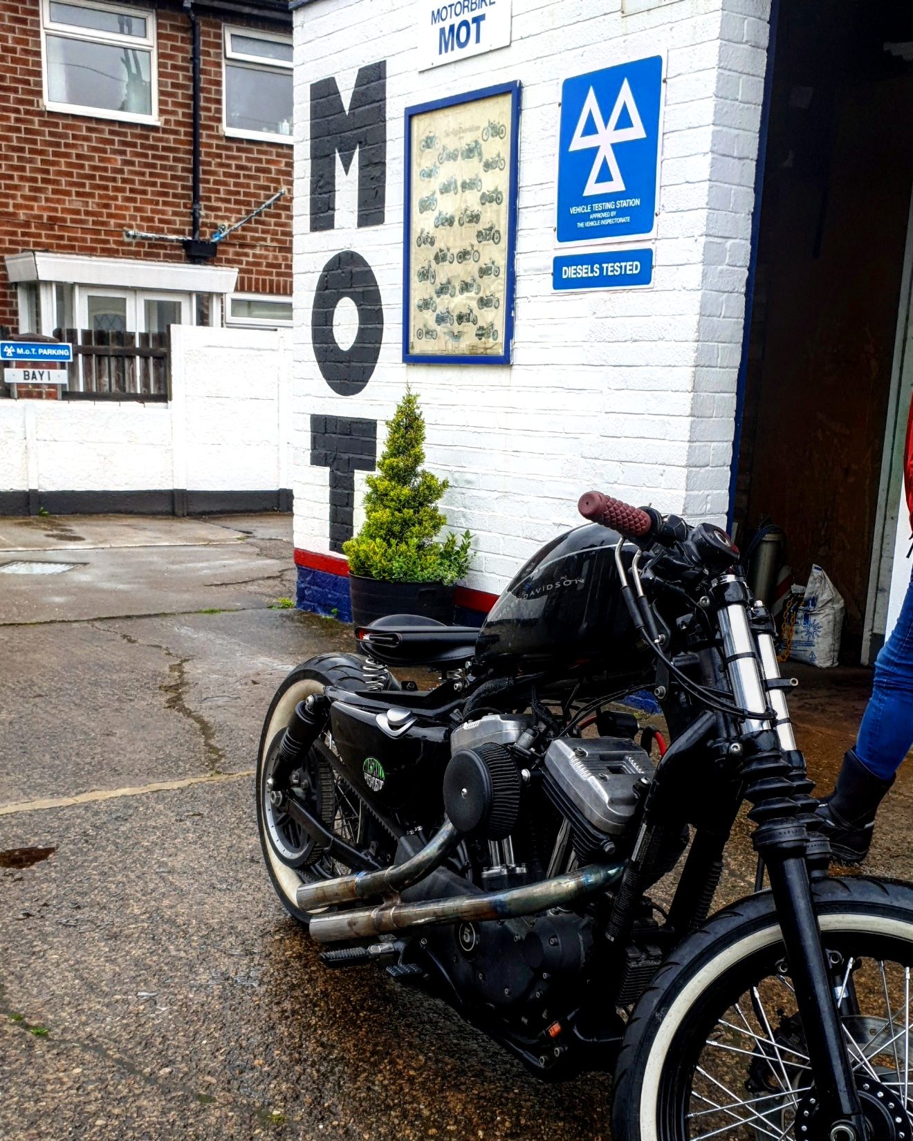 A black custom motorbike beside the MOT wall